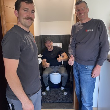 Erstes Probesitzen auf dem neuen Geberit AquaClean Mera Dusch-WC. Professionell installiert von Dieter Holzapfel (rechts im Bild) und Patrick Hofer (links im Bild) von der Firma Holzapfel in Bürmoos. (c) Sascha Huber